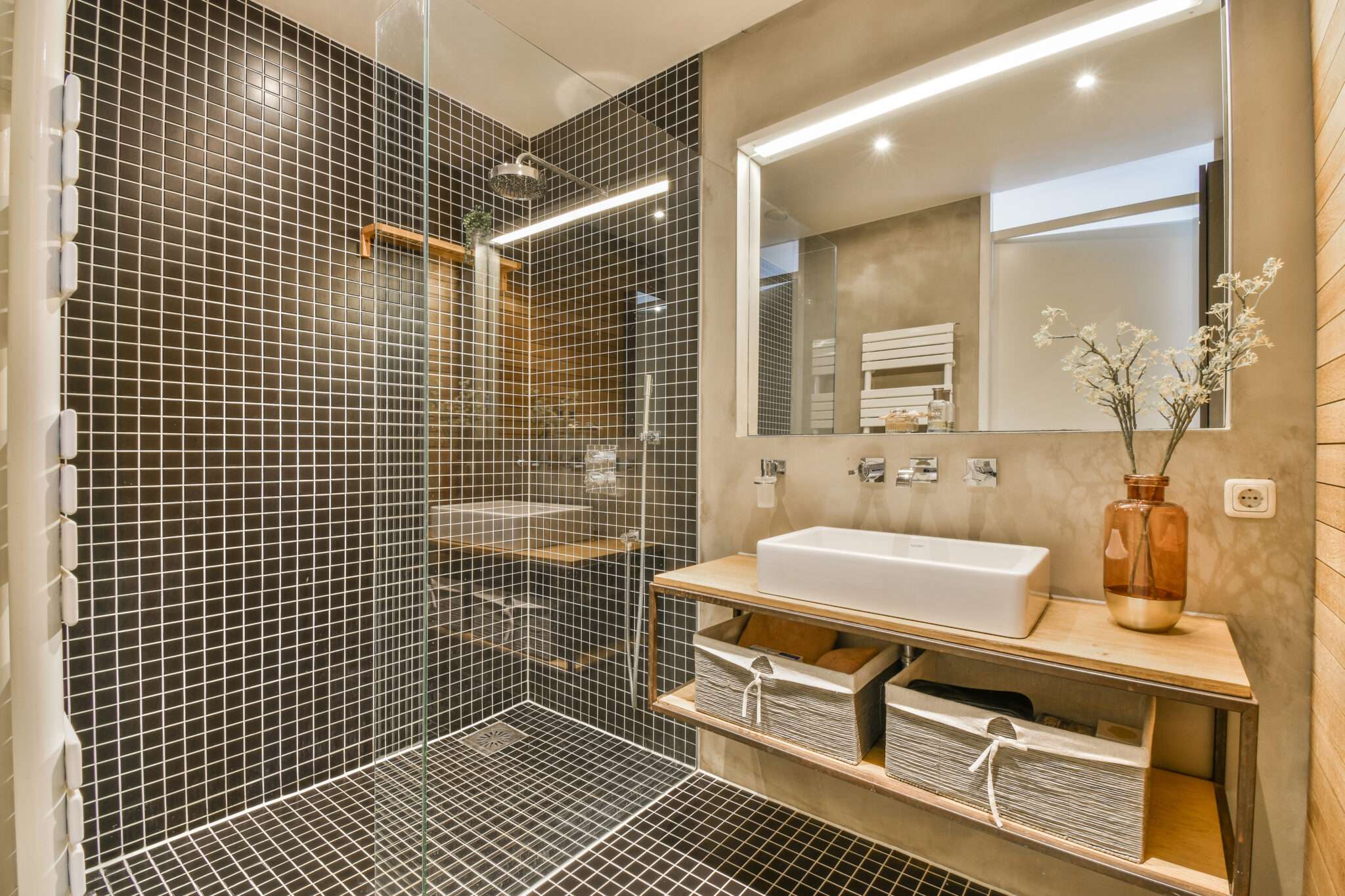 Glass shower door in black tile bathroom