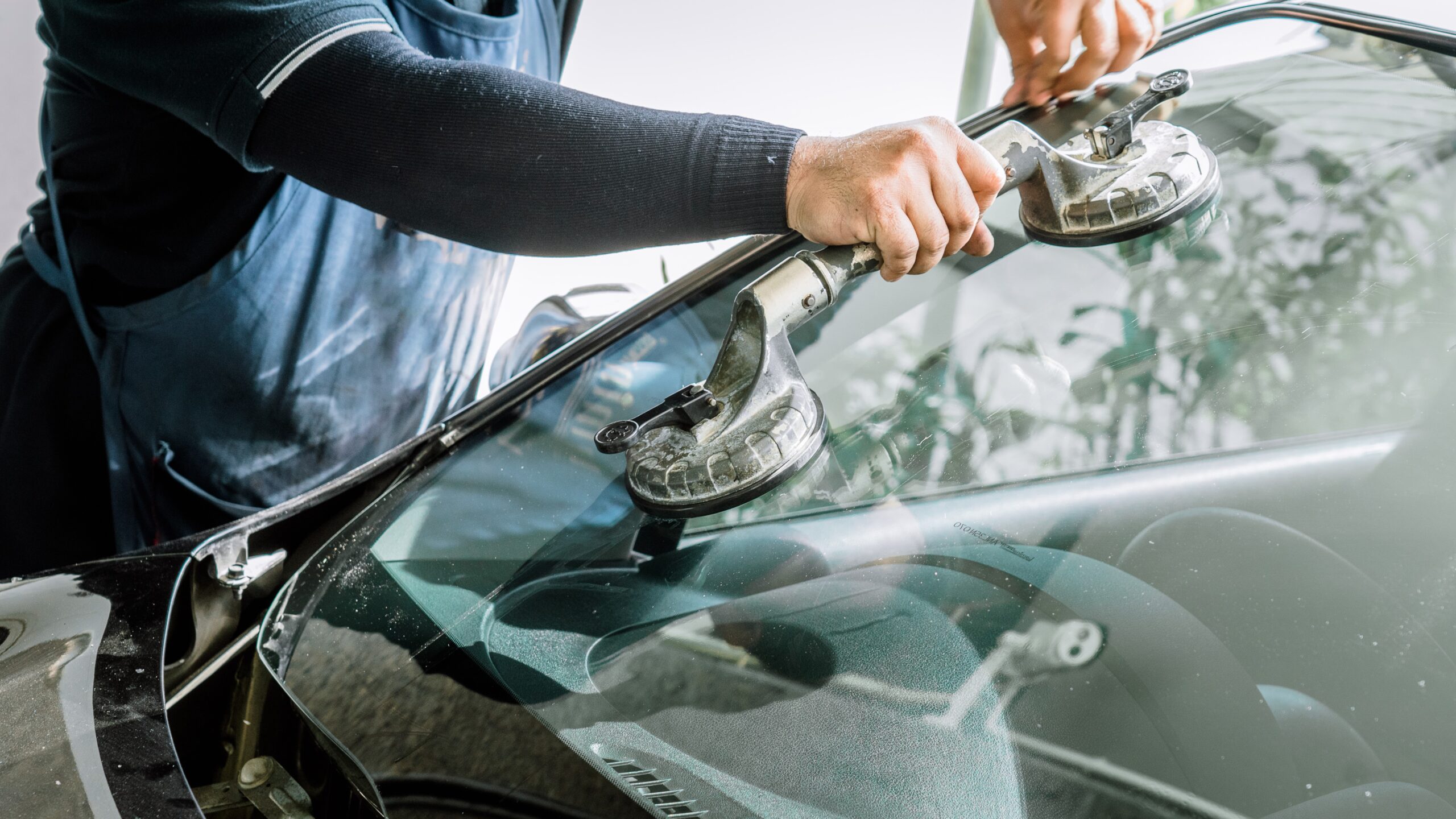 Close view of a technician positioning a replacement windshield